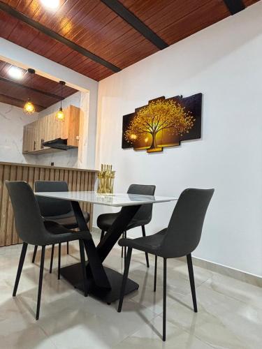 Apartamento Jardines Guaduas Cundinamarca في غوادواس: طاولة غرفة طعام مع كراسي وشجرة على الحائط