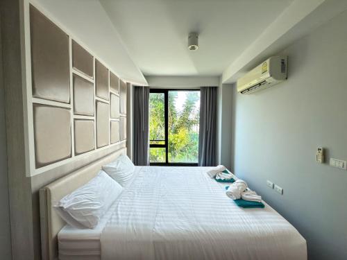 ein Schlafzimmer mit einem großen weißen Bett mit einem Fenster in der Unterkunft 6th Avenue 2 bedroom in Surin Beach