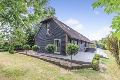 a small black house with a wooden deck at Frith Farm House Cottages in Newnham