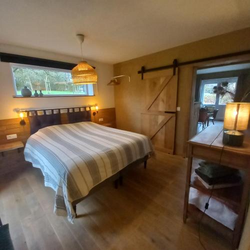 a bedroom with a bed and a desk and a window at Le verger d' Adèle in Vielsalm