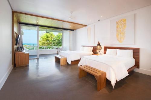 a bedroom with two beds and a balcony at Ibagari Boutique Hotel in Roatan