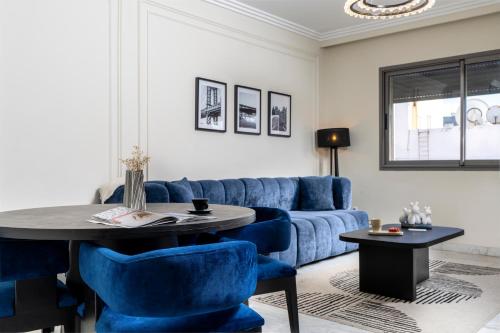 The Loft Residence by GoodMove - Maarif Casablanca في الدار البيضاء: غرفة معيشة مع أريكة زرقاء وطاولة