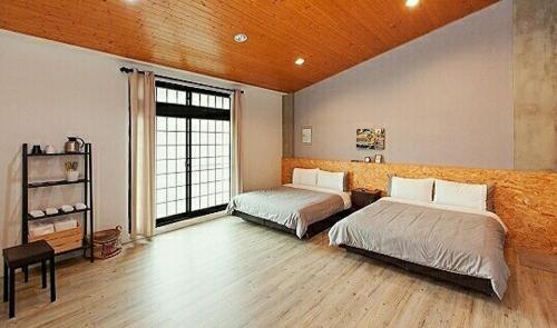 een slaapkamer met twee bedden en een groot raam bij 約旦河民宿包棟附電動麻將 in Hsia-ch'ing