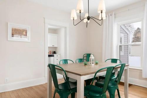 a dining room with a wooden table and green chairs at Sweet Retreat 3 Mins to Notre Dame Eddy St Commons and Memorial Hospital in South Bend