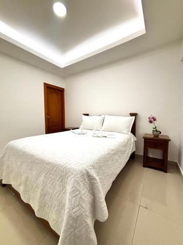 a bedroom with a large white bed with white sheets at Hotel Sleep Well in Filandia