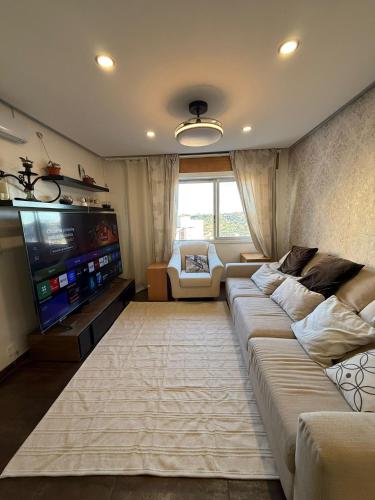 Una sala de estar con un sofá y un televisor de pantalla plana. en DhaliHOUSE, en Mealhada