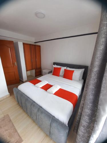 a bedroom with a large bed with red and white pillows at Delightfulstaycation in Nanyuki