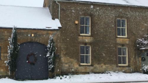a brick house with a door in the snow at Three private rooms in the Master Suite, Cotswolds Coaching Inn - Traveller Awards Winner 2026 in Naunton