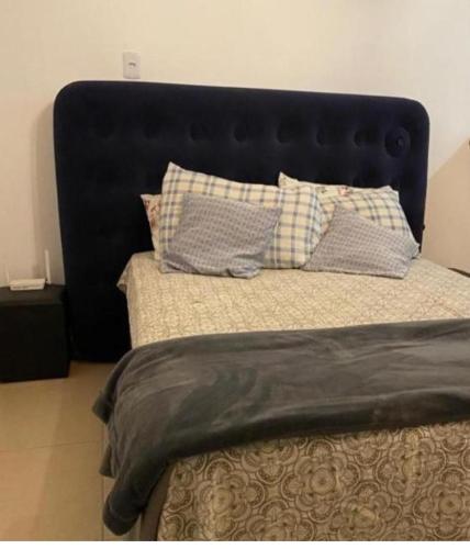 uma cama com cabeceira preta e almofadas em Casa com excelente acomodação em Itatiaia