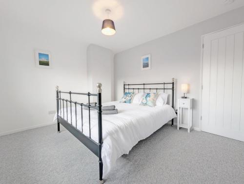 Pickleberry Cottage - Close to sandy beach في ويست ويتيرينغ: غرفة نوم بسرير أسود مع شراشف ووسائد بيضاء