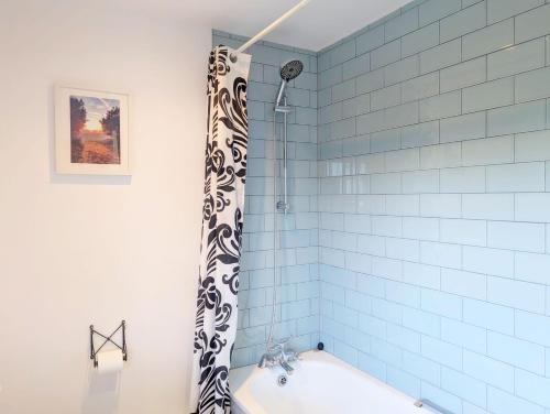 Pickleberry Cottage - Close to sandy beach في ويست ويتيرينغ: حوض استحمام مع ستارة دش سوداء وبيضاء