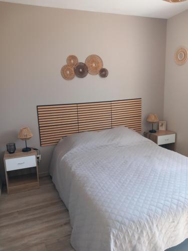a bedroom with a white bed and two night stands at Maison vacance proche ste mère église in Picauville