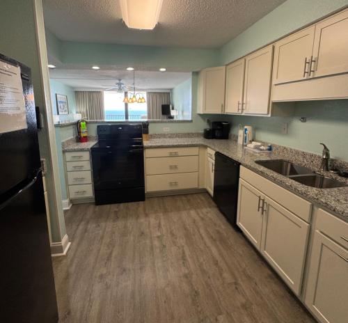 a kitchen with white cabinets and black appliances at Club Regency at Regency Towers in Myrtle Beach