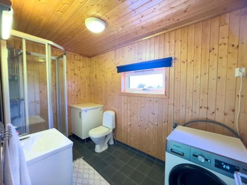 a bathroom with a toilet a sink and a washing machine at Littahuset in Moskenes