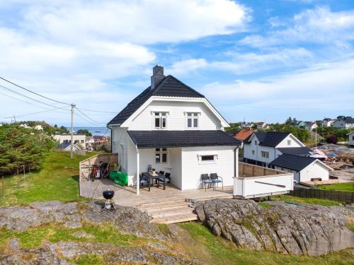 a white house with a deck on a rock at Littahuset in Moskenes