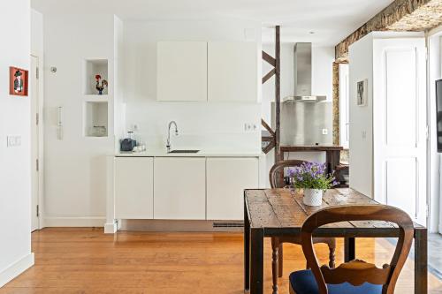 a kitchen with white cabinets and a wooden table at 54 Santa Catarina Apartments in Lisbon