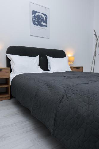 a bed with a black comforter and white pillows at Escape Studio 4 Pollux Militari in Chiajna