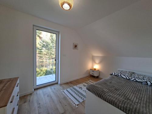 Un dormitorio con una cama y una ventana grande. en Lake House Szteklin, en Szteklin