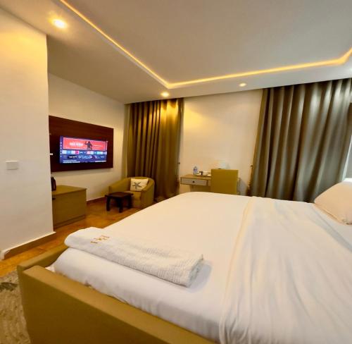 Un dormitorio con una gran cama blanca y un televisor. en Beauties And Hunks hotel - B&H, en Abuja