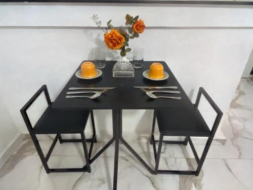 een zwarte tafel met daarop een vaas met oranje bloemen bij Recanto do Vale in Diamantina