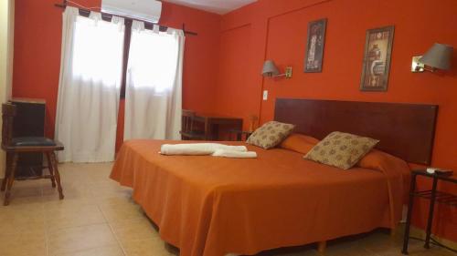 1 dormitorio con 1 cama con paredes de color naranja en Toneles - Cafayate, en Cafayate