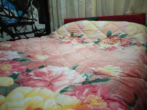 a bed with a pink and white quilt with flowers on it at Habitación doble- cama dos plazas in Los Ángeles
