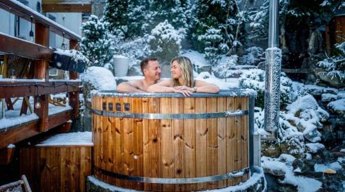 a man and woman sitting in a hot tub in the snow at Karkonoski SPA - Bufet mini All Inclusive gratis! in Karpacz