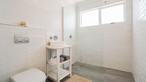 a white bathroom with a toilet and a sink at Hideaway in Herolds Bay