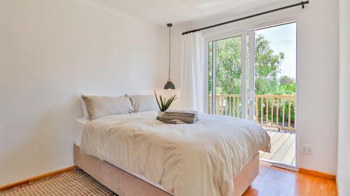 a bedroom with a bed and a large window at Hideaway in Herolds Bay