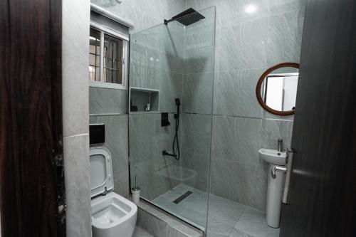 a bathroom with a shower and a toilet and a sink at The Mason by Trovardig in Abuja