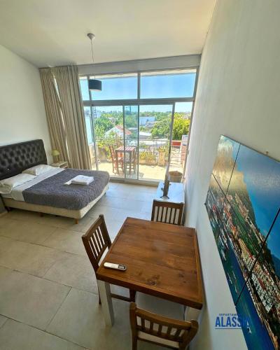 a bedroom with a bed and a table and a bed and a view at Departamento Alassio in Tigre