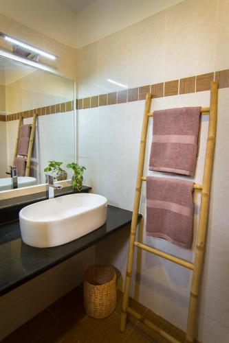 a bathroom with a sink and a shelf with towels at Le Kroma Villa in Phumĭ Prêk