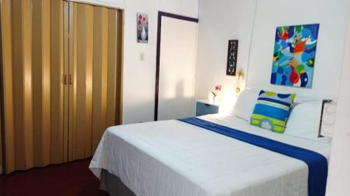 una camera da letto con un grande letto bianco con una coperta blu di Cómodo Céntrico y Confortable a Managua