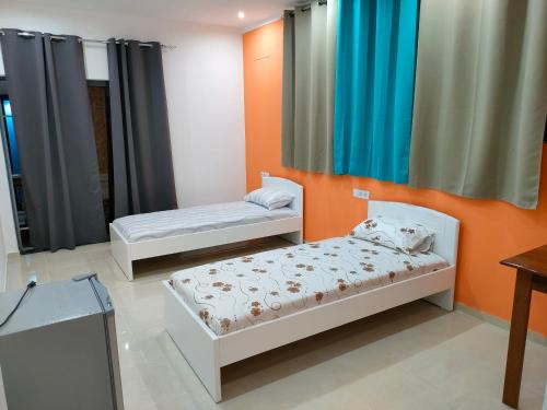 two beds in a room with orange and blue curtains at Residencial oliveira in Porto Novo