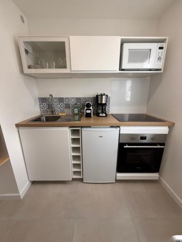 a small kitchen with a sink and a microwave at Cozy T2 - L'Herbaudière - 200m de la plage in Noirmoutier-en-l'lle