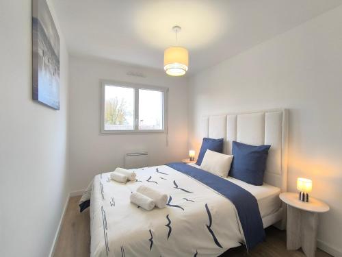 een slaapkamer met een groot bed met blauwe kussens bij L'Océan - Ambiance Apaisante & Rafraichissante in Biville-sur-Mer