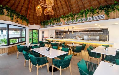 a restaurant with white tables and green chairs at Cancun Bay All Inclusive Hotel in Cancún