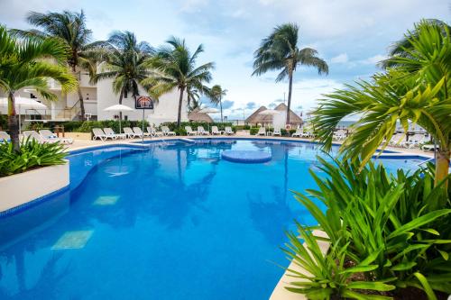 a large swimming pool with palm trees and chairs at Cancun Bay All Inclusive Hotel in Cancún
