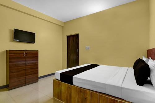 a bedroom with a bed and a tv on the wall at POP 84107A Hotel O J J Lodge in Āsansol