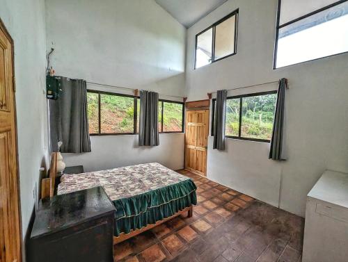 a bedroom with a bed in a room with windows at Villa Piedra Viva in Tilarán