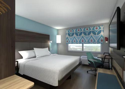 a bedroom with a bed and a chair and a window at Tru By Hilton Norwalk Des Moines in Norwalk