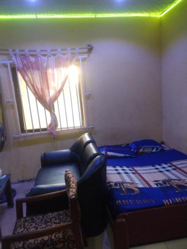 a bedroom with a couch and a bed and a window at Ensuite in Ejigbo