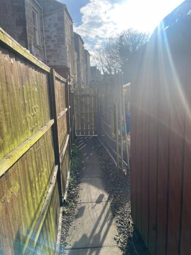 Garden Room at Tartan House في إينفيرنيس: سياج ورصيف تشرق من خلالهما الشمس