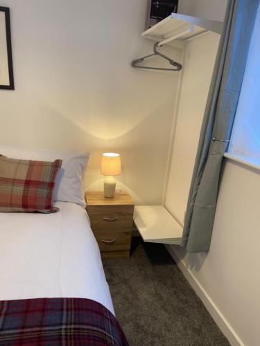 Garden Room at Tartan House في إينفيرنيس: غرفة نوم بسرير ومصباح على موقف ليلي