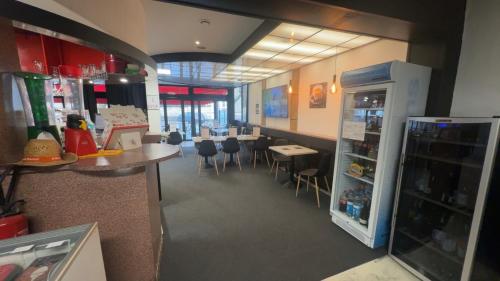 a room with a restaurant with a counter and a refrigerator at GOOD NIGHT HÔTEL By L'excess in Vierzon