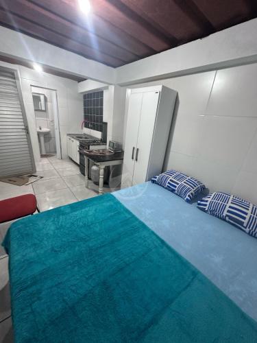 a bedroom with a blue bed and a kitchen at Container Porto Alvorada in Imbituba