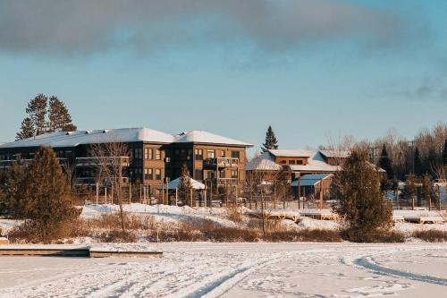 a large building in the snow with a road in front at Lakefront Mountain View - Resort Loft in Lac-Superieur