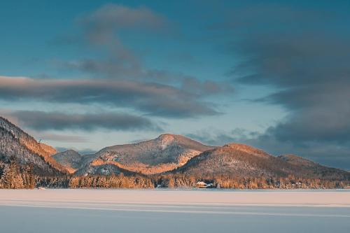 a large body of water with mountains in the background at Lakefront Mountain View - Resort Loft in Lac-Superieur