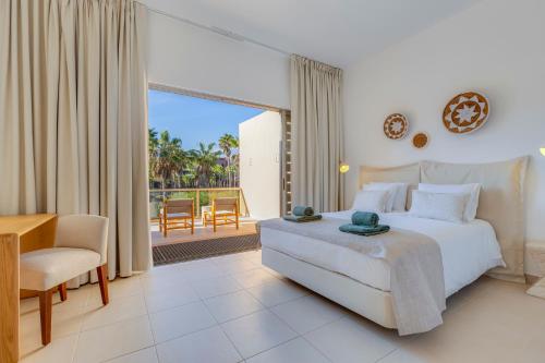Un dormitorio con una cama y un escritorio y un balcón. en SALGADOS BEACH VILLA by My Algarve Rentals, en Bicas