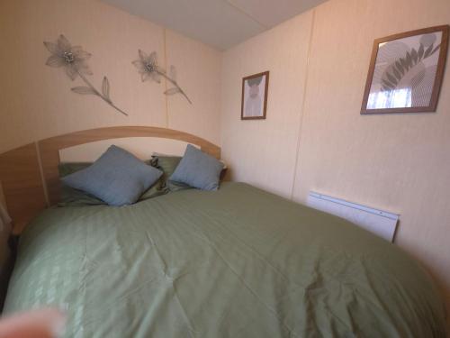 a bedroom with a green bed with flowers on the wall at The Retreat Finch - Marine Holiday Park in Rhyl